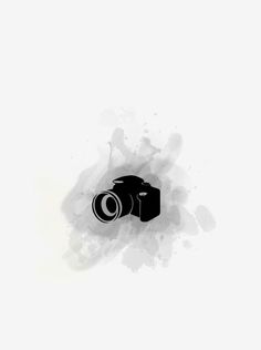 a black and white photo of a camera on the ground with paint splatters around it