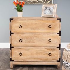 a wooden dresser with three drawers and two pictures on top