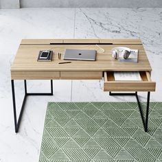 an office desk with a laptop and other items on it, sitting in front of a marble wall