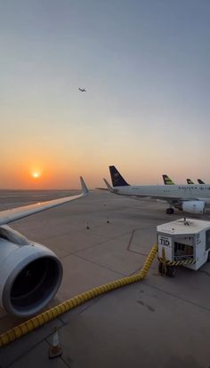 an airport tarmac with planes parked on the runway at sunset or dawn, and one plane is being refueled