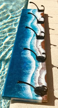 a blue bench sitting on top of a swimming pool next to the ocean and water