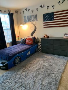 a race car bed is in the middle of a room with a flag on the wall