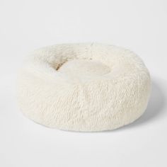 a white dog bed that is made out of sheepskin and has a round shape