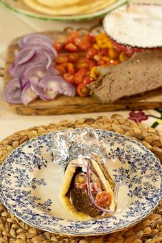 a plate with some food on it next to bread and other foods in the background