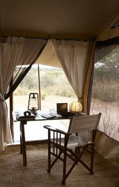 a table and chairs in front of a window with curtains on the outside, overlooking an open field