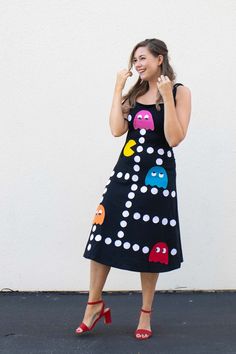 a woman in a black dress is talking on her cell phone while standing next to a white wall