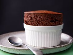 a chocolate cake sitting on top of a white plate with a spoon next to it