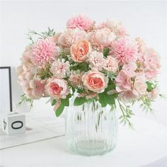 a glass vase filled with pink flowers on top of a white table next to a mirror