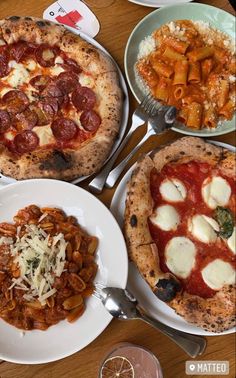 three different types of pizzas on plates next to wine glasses and utensils