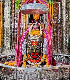 an idol is sitting in the middle of a stage with flowers and garlands around it