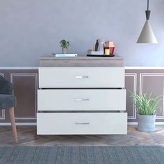 a white dresser sitting next to a gray chair and potted plant on top of it