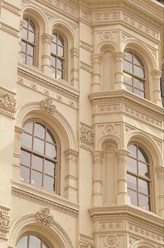 a clock on the side of a building with many windows and balconies in front of it