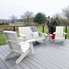 two white adiron chairs sitting on top of a wooden deck next to a potted plant