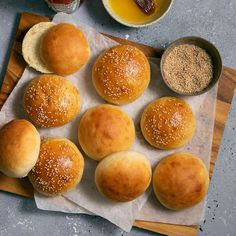 six buns with sesame seeds and other ingredients on a cutting board