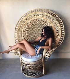 a woman sitting in a wicker chair with her legs crossed on the floor and one leg up