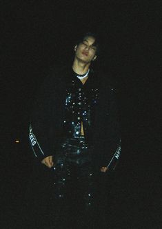 a man standing in the dark with his hands on his hips wearing black leather pants