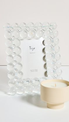 a candle sits next to a clear glass frame