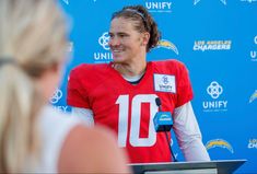 a man in a red jersey is talking to the presser at a press conference