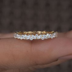 a person's hand holding a gold and diamond wedding band