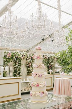 a wedding cake sitting on top of a table in a room with chandeliers