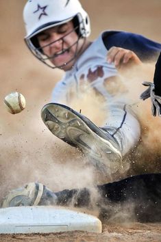 a baseball player sliding into the base with his glove and ball in mid - air