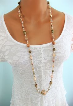 Long beige and gold beaded necklace for women. Handmade jewelry for women by Ralston Originals. This beautiful beige necklace is perfect for a formal occasion, as wedding jewelry, or for everyday. It's loaded with many different beads; crystal, pearl, natural stone, glass, gold metal, clay, and acrylic. The unique focal bead at the bottom is a clay bead with gold metal details, tiny pearl beads, and crystal rhinestones. This necklace is 40 inches long, and has a lobster clasp. Necklace can be ma Elegant Beige Beaded Necklaces With Colorful Beads, Elegant Beige Beaded Necklace With Colorful Beads, Beige Jewelry With Colorful Beads For Jewelry Making, Beige Beaded Chain Necklace With Round Beads, Elegant Beige Beaded Necklaces With Large Beads, Elegant Beige Beaded Necklace With Large Beads, Elegant Beige Jewelry With Large Beads, Bohemian Single Strand Gold Beads, Beige Beaded Necklace With Gold Round Beads