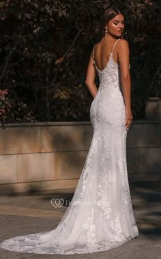 a woman in a white wedding dress standing on the street with her back to the camera