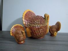 three ceramic turkeys sitting on top of a wooden table