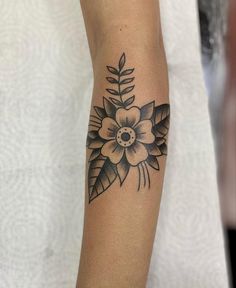 a woman's arm with a black and white flower tattoo on the left forearm