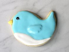 a cookie shaped like a blue whale on a marble counter top with white icing