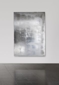 an abstract painting hanging on the wall in a white room with black and grey flooring