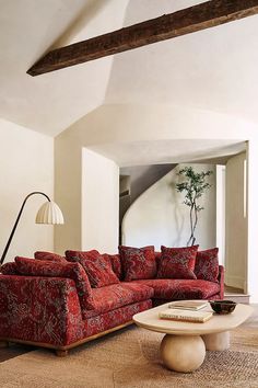 a living room with red couches and pillows on top of the sofa, in front of a large window