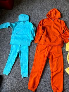 two children's clothing laying on the floor next to each other in different colors