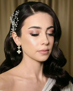 a woman with dark hair wearing a tiara and eye makeup looks off to the side