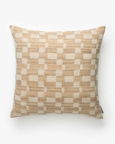 a tan and white checkered pillow on a white background