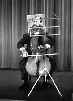 a man sitting on top of a chair holding a cello