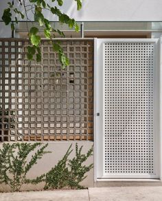 an open white door sitting on the side of a building next to a green plant