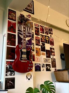 a guitar is hanging on the wall next to a potted plant in front of it