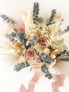 an arrangement of flowers and foliage on a white background with pink ribbon in the corner