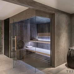 a bathroom with a glass shower door and stone flooring, along with a large vase on the side of the bathtub