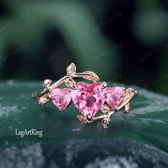 two pink heart shaped gems are on top of a leafy green surface with leaves