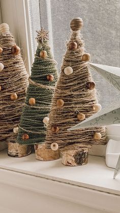 three small christmas trees made out of twine and burlocks on a window sill