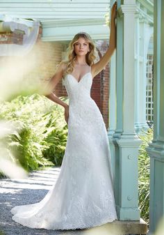 a woman in a wedding dress posing for the camera with her hand on her hip