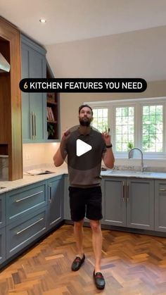 a man standing in the middle of a kitchen holding his hands up and pointing to the camera