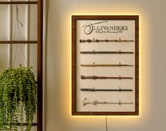 a wall mounted display with many different types of wands and needles on it in front of a potted plant