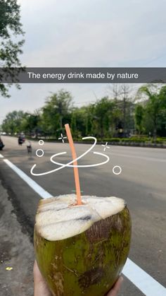 a person holding up a green coconut with a straw in it