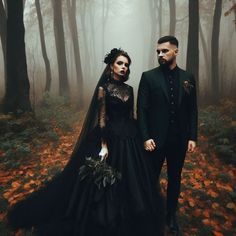 a man and woman dressed in black standing next to each other on a forest floor