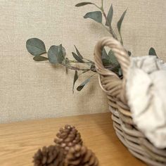 a basket filled with pine cones and greenery sitting on top of a wooden table