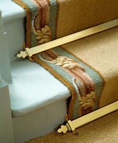 a carpeted stair case with two gold rails on the top and bottom of it