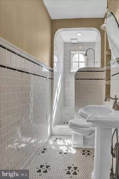 a bathroom with two sinks and a toilet next to a window in the wall above it